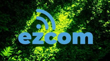 Blue text “ezcom” with a wireless symbol above it is centered over a background of vibrant green foliage. The image conveys a sense of technology and nature.