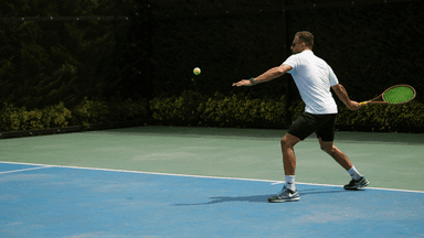 Tennis player preparing to hit a ball on a court with a net backdrop