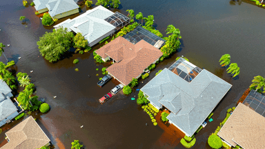 Aerial view of flooded suburban homes with water covering driveways and yards