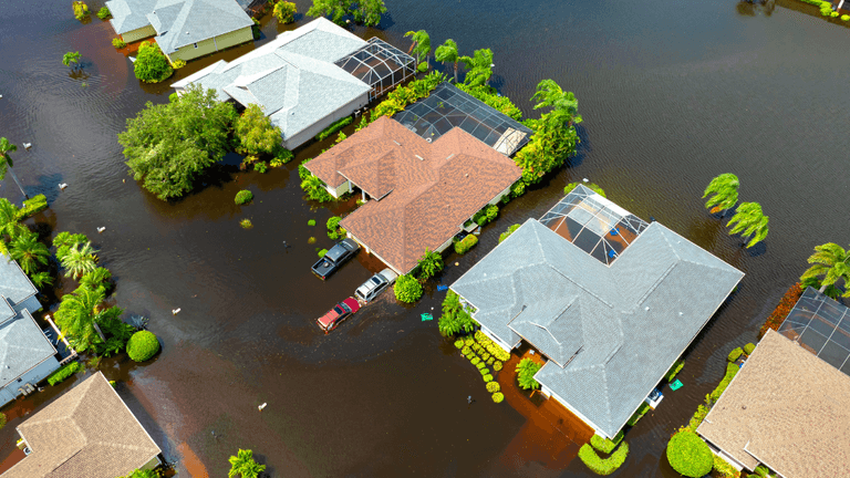 Aerial view of flooded suburban homes with water covering driveways and yards