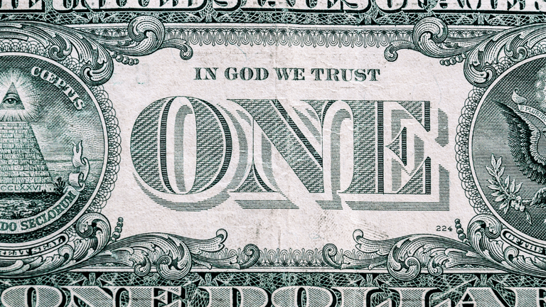 Close-up of a one-dollar bill featuring the motto "In God We Trust"