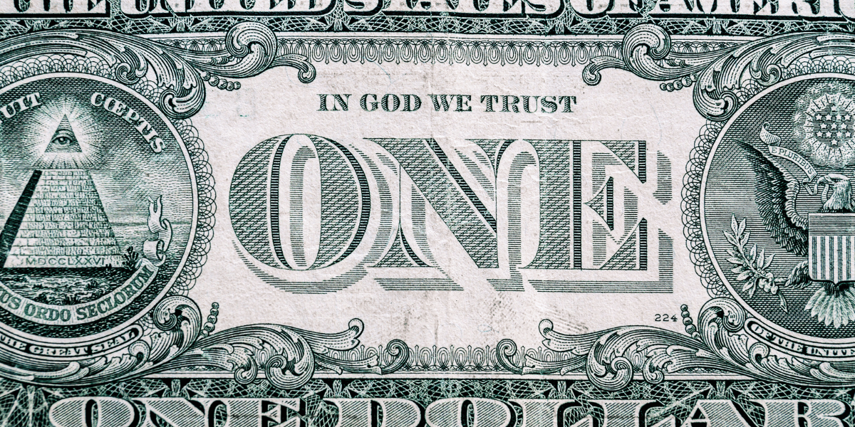Close-up of a one-dollar bill featuring the motto "In God We Trust"