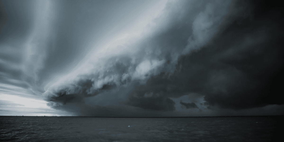 Dramatic dark storm clouds looming over a calm ocean landscape, creating a moody atmosphere