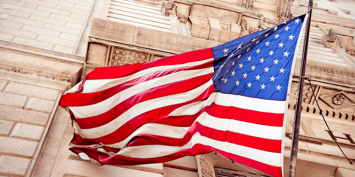 American flag waving outside an ornate stone government building.